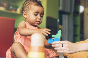About happy baby playing with toy blocks.