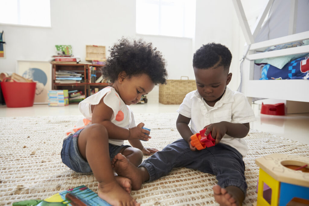 Our Curriculum baby boy and girl playing with toys in playroom together